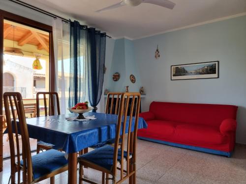 een woonkamer met een tafel en een rode bank bij Appartamento Via Toscana in Budoni