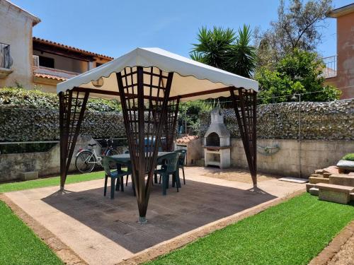 een tafel en stoelen onder een prieel in een tuin bij Appartamento Via Toscana in Budoni