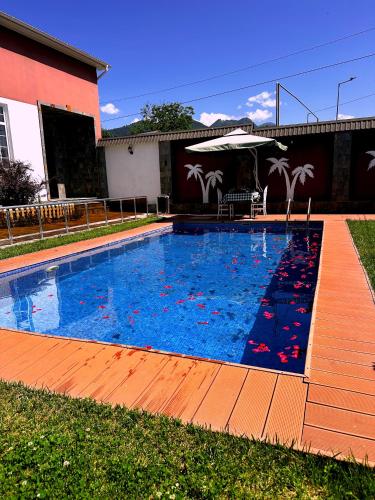 a large swimming pool with a deck and an umbrella at Qafqaz Fountain Villa in Gabala