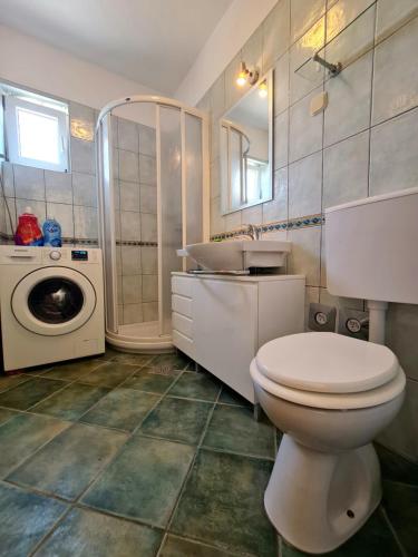 uma casa de banho com um WC, um lavatório e uma máquina de lavar roupa em Apartments Roko em Zadar
