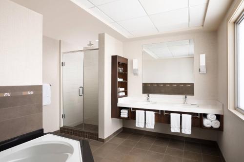 een badkamer met een bad, een wastafel en een spiegel bij Delta Hotels by Marriott Calgary South in Calgary