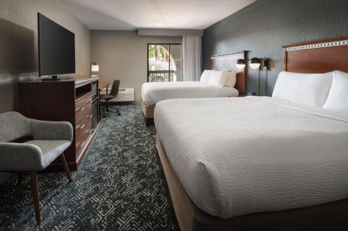 a hotel room with two beds and a chair at Four Points by Sheraton Tucson Airport in Tucson