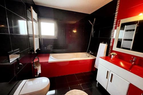 uma casa de banho vermelha e preta com uma banheira e um WC em Casa Castelhano - Minho Braga em Mire de Tibães