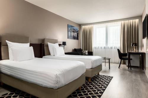 パリにあるAC ホテル パリ ポルト マイヨ バイ マリオットのベッド2台とデスクが備わるホテルルームです。
