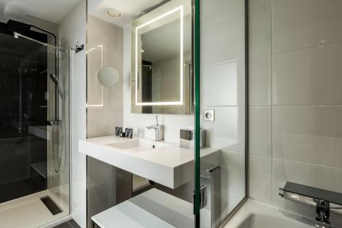 a white bathroom with a sink and a shower at AC Hotel Paris Porte Maillot by Marriott in Paris