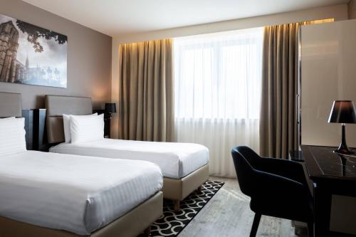 a hotel room with two beds and a desk at AC Hotel Paris Porte Maillot by Marriott in Paris