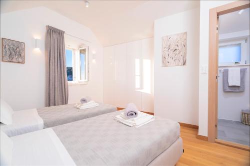 um quarto branco com 2 camas e uma janela em Villa Moscatello em Hvar