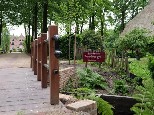 a wooden walkway with a sign in a garden at Landgoedhoeve Vosbergen in Heerde