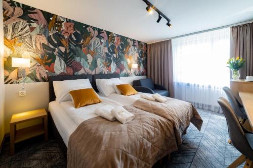 a hotel room with a large bed and a mural at Hotel Jubilat in Zamość