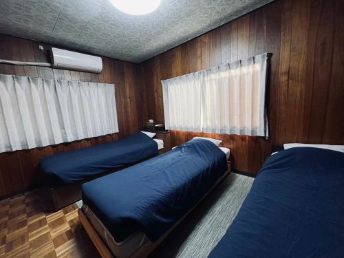 twee bedden in een kamer met houten lambrisering bij SUMITSUGU HOUSE Grandpa in Kumamoto