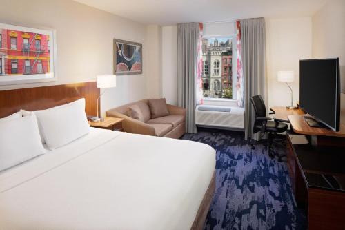 a hotel room with a large bed and a couch at Fairfield Inn & Suites New York Manhattan/Downtown East in New York