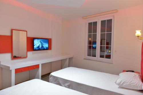 a bedroom with two beds and a desk with a mirror at Grand Beyaz Saray Otel in Duzce