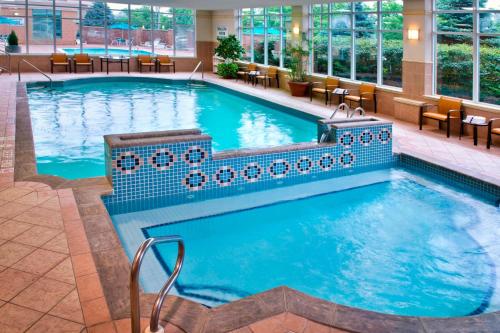 ein großer Pool in einem Hotel mit Stühlen und Tischen in der Unterkunft Courtyard by Marriott Niagara Falls in Niagara Falls