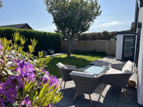 a patio with a table and chairs and flowers at Stylish Modern Home with Parking Enclosed Garden in Holyhead