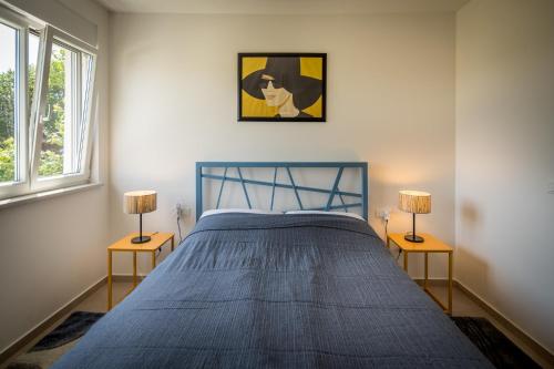 a bedroom with a blue bed with two lamps at Villa Skrila in Fažana