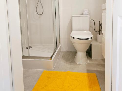 a bathroom with a shower and a toilet with a yellow rug at Sweet Dream in Gdańsk