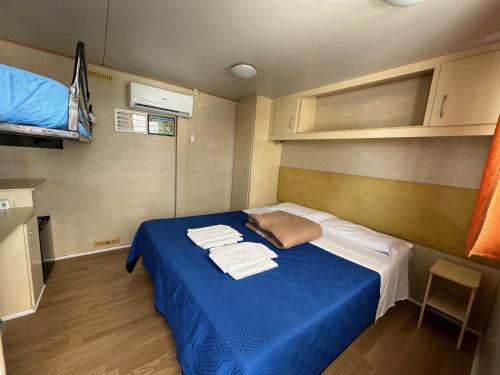 una piccola camera con un letto blu con asciugamani di TAHITI a Fondi