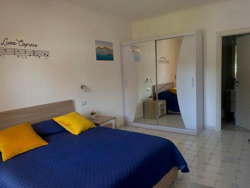 a bedroom with a blue and yellow bed and a mirror at Capri Melody in Anacapri