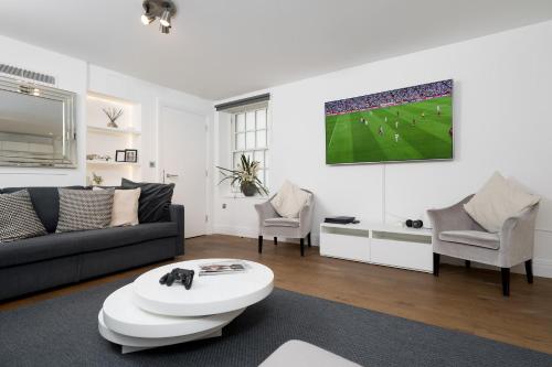 a living room with a couch and a soccer game at Aircon 2 Bedr, 3 Beds, 2 Bath Covent Garden, Subway in London