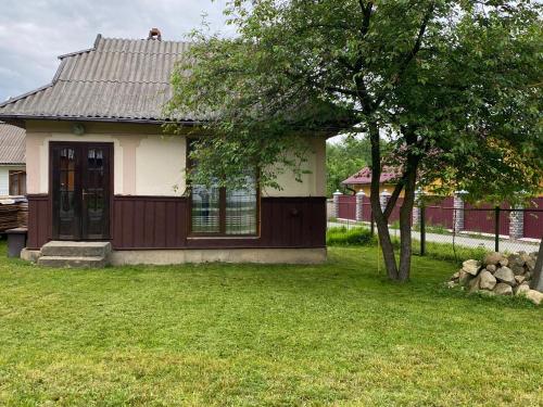 ein kleines Haus mit einem Baum im Hof in der Unterkunft Біля річки in Scheschory