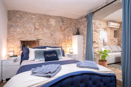 een slaapkamer met een blauw bed en een stenen muur bij Unique Stone House Apartment -Free parking in Stari Grad