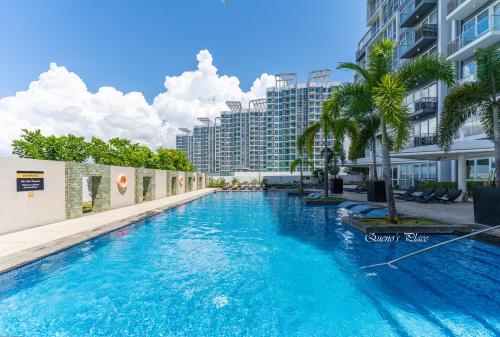 a swimming pool with palm trees and buildings at Mactan Newtown - 1BR Stunning Ocean View and City View in Mactan