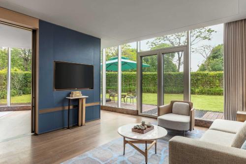 a living room with a tv and a couch and a table at Midea Shunde, a Tribute Portfolio Hotel in Shunde