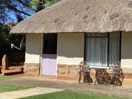 a hut with two chairs and a table in front of it at Ledges Retreat in Bergville