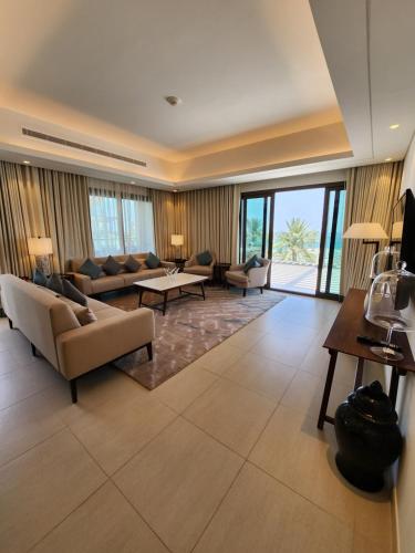 una gran sala de estar con sofás, mesas y ventanas. en The Address Residences Fujairah en Fujairah