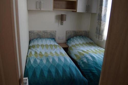 2 Betten befinden sich in einem kleinen Zimmer. in der Unterkunft River View Retreat in Offenham