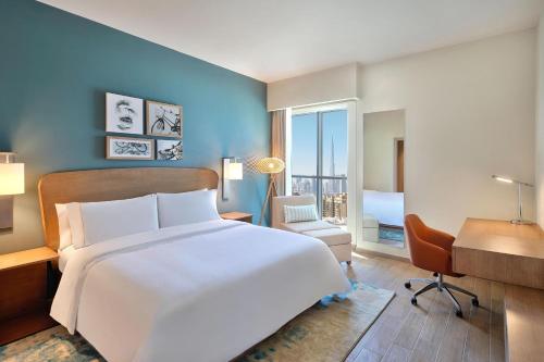 a bedroom with a large white bed and a desk at Element Al Jaddaf, Dubai in Dubai