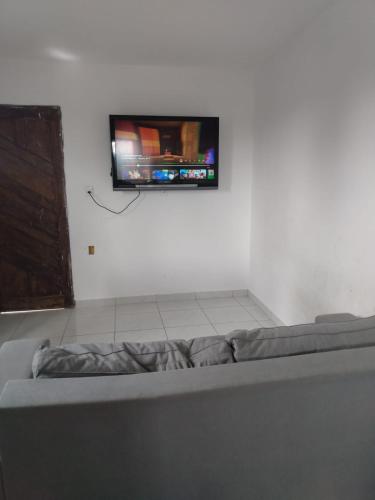 TV de pantalla plana en una pared sobre una cama en Apartamento temporada para São joao en Campina Grande