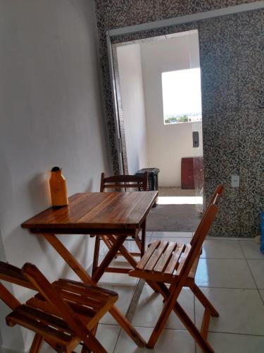 una mesa de madera y sillas en una habitación con ventana en Apartamento temporada para São joao, en Campina Grande