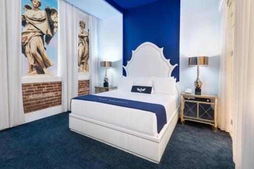 a bedroom with a white bed and blue walls at The Saint Hotel, New Orleans, French Quarter, Autograph Collection in New Orleans