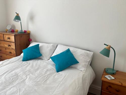 a bedroom with a white bed with blue pillows at Seaside Rooms Gorleston in Gorleston-on-Sea