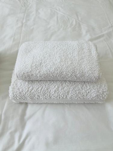 a white towel laying on top of a bed at Seaside Rooms Gorleston in Gorleston-on-Sea