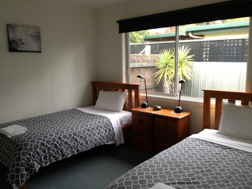 1 dormitorio con 2 camas individuales y ventana en Phillip Island Cottages, en Cowes