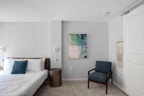 a bedroom with a bed and a blue chair at CozySuites l 2BR Loft, Monument Circle, Indy in Indianapolis