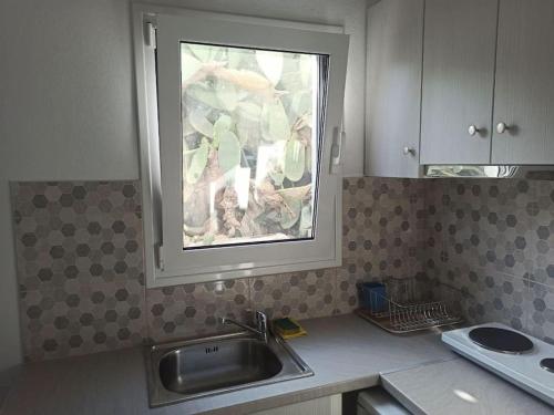 cocina con fregadero y ventana en Δίκλινο δωμάτιο Δονούσα με εξαιρετικό μπαλκόνι en Donoussa