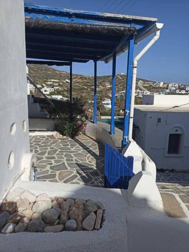 a building with a blue roof and a stone patio at Δίκλινο δωμάτιο Δονούσα με εξαιρετικό μπαλκόνι in Donoussa