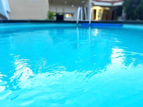 einen Pool mit blauem Wasser vor einem Haus in der Unterkunft shirly three bedroom house in Herzlia