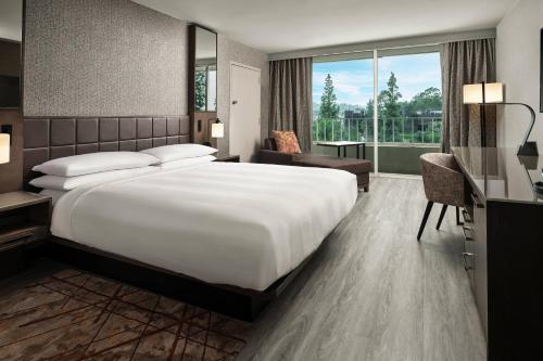 Habitación de hotel con cama grande y ventana grande. en Warner Center Marriott Woodland Hills, en Woodland Hills