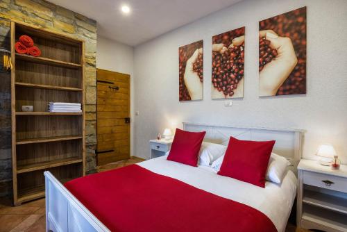 1 dormitorio con 1 cama grande con almohadas rojas en TouristFarm - apartments "RED FAIRYTALE" en Marezige