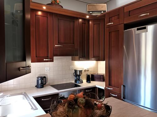 a kitchen with wooden cabinets and a stainless steel refrigerator at ZENIA Pelion garden house in Platanidia