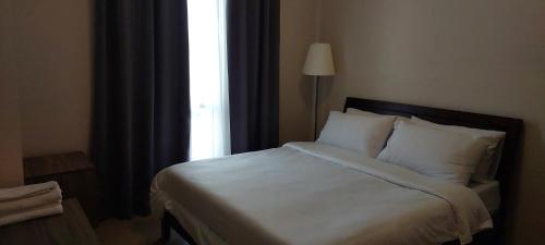 - une chambre avec un lit doté de draps blancs et une fenêtre dans l'établissement 81 Newport,NAIA 3,Pasay Condotel, à Manille