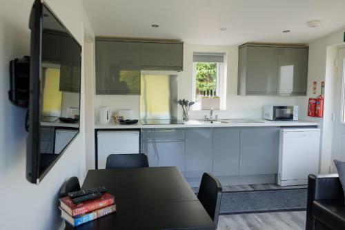 a kitchen with white cabinets and a black table at Ardvreck Chalet self-catering in Kyleakin