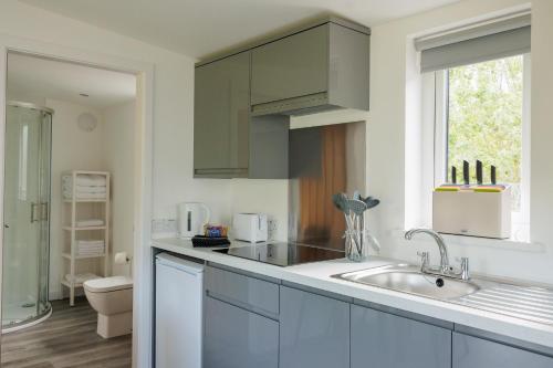 a white kitchen with a sink and a window at Ardvreck Chalet self-catering in Kyleakin