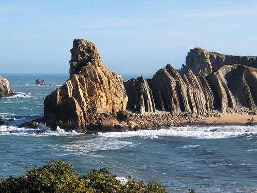 una formación rocosa en el océano con una playa en APARTAMENTO LA PICOTA, en Liencres