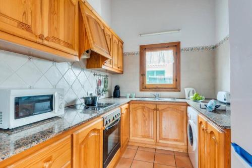 eine Küche mit Holzschränken und einer Mikrowelle in der Unterkunft Villa Mar. En Ciudadela Menorca in Cala'n Bosch
