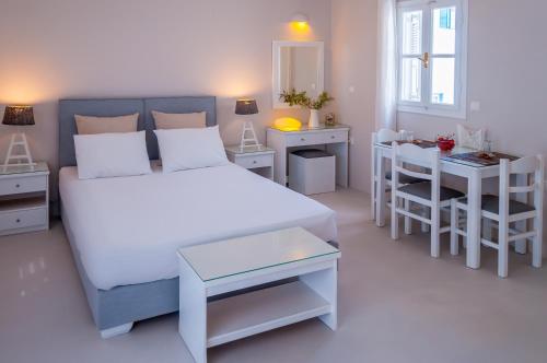 a bedroom with a bed and a table and a desk at Milos Bay Suites in Adamantas